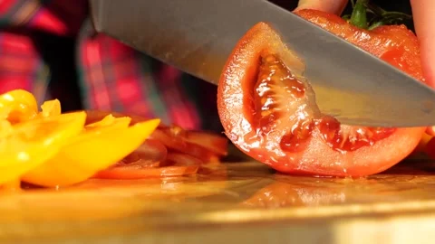 Woman's hands in kitchen cutting fresh tomato on wooden cutting board Stock-Footage 147934925
