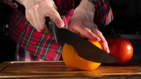 Woman's hands in kitchen cutting fresh tomato on wooden cutting board Stock Footage 147935423