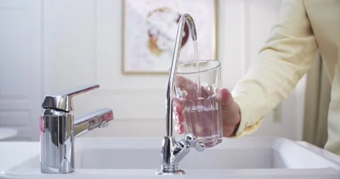 Woman’s hands in the kitchen draw filtered water from a filter faucet Vidéo 230644729