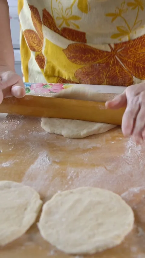 Womans hands kneading and rolling fresh raw dough on a wooden board sprinkled 库存影片 343910362