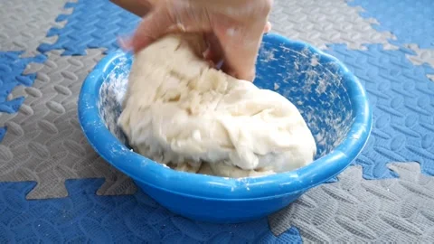 Woman's hands kneading white bread dough in a bright blue plastic mixing bowl Stock Footage 320150159