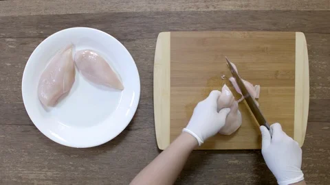 Woman`s hands with a knife slices a chicken fillet on a wooden cut board Stock-Footage 122201366