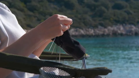 Woman's hands knitting a sock by the sea Stock Footage 329068578