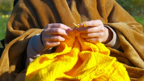 Woman's hands knitting yellow wool outdoors Stock Footage 330662732