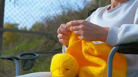 Woman's hands knitting yellow wool outdoors Stock Footage 330663402