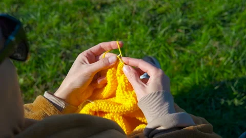 Woman's hands knitting yellow wool outdoors Stock Footage 330665333