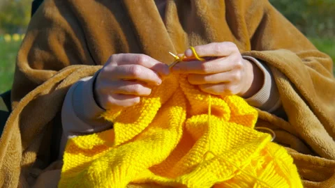 Woman's hands knitting with yellow wool outdoors Video stock 344315071