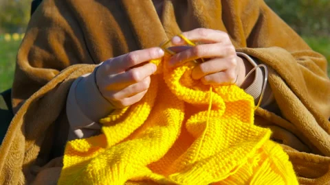 Woman's hands knitting yellow yarn outdoors. Stock Footage 332968898