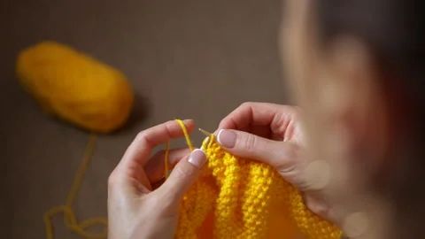 Woman's hands knitting with yellow yarn Stock Footage 332985474