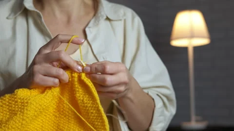 Woman's hands knitting yellow yarn indoors Stock Footage 334752005