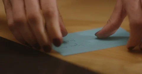 A woman's hands lift up a blue and purple note card and fold it in half. Stock Footage 101257597