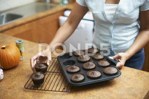 Womans Hands Lifting Cup Cakes Onto Cooling Rack