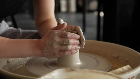 Woman's hands making a clay vase on a potter's wheel in a workshop. Video stock 267820400
