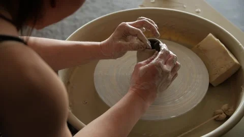 Woman's hands making a clay vase on a potter's wheel in a workshop. Stock Footage 267820635