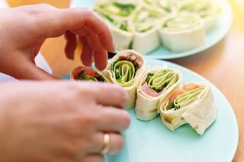 Woman's hands making rolls with red fish and vegetables Stock Photos