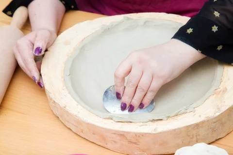 Woman's hands with metallic tool  making a white clay plate Stock Photos