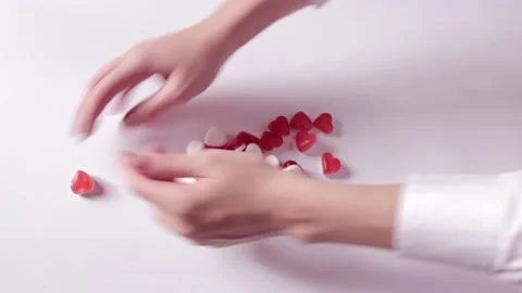 Woman's hands mix the word love from jelly sweets in hearts form and collect Stock Footage 231370341