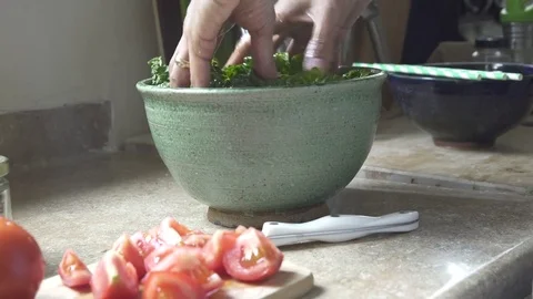 Woman's hands mixing kale in ceramic salad bowl in kitchen Video stock 79548143