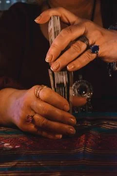 Woman's hands mixing a tarot card maze with jewelery on her fingers. Occultis Stock Photos