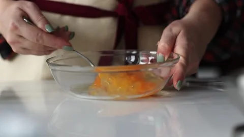 Woman's hands mixing two eggs in transparent plate. Slow motion Stock Footage 231794396