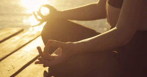 Woman's hands in namaste mudra pose during meditation on river pier at sunset. Vídeo Stock 112043971