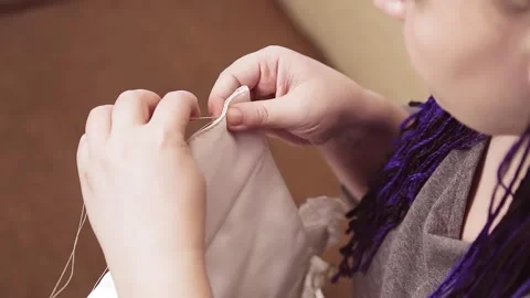 A woman's hands with a needle and thread sew a wedding dress Stock Footage 150439249