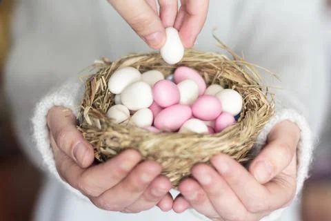 Woman's hands offering Easter almonds in bird's nest Stock Photos