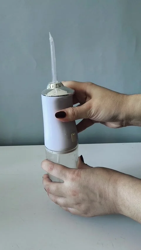 A womans hands open the irrigator to pour water into a glass. Using an irrigator Vidéo 329969591