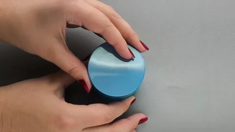 A womans hands open the lid of a jar of cream on a gray table. Moisturizing Video stock 324554141
