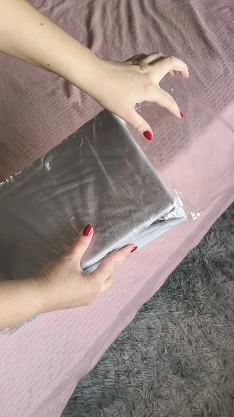 A womans hands open a package with a new sheet with an elastic band against the Stock Footage 327456999