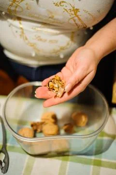 Woman's hands open up pecan nuts in a bowl Stock Photos