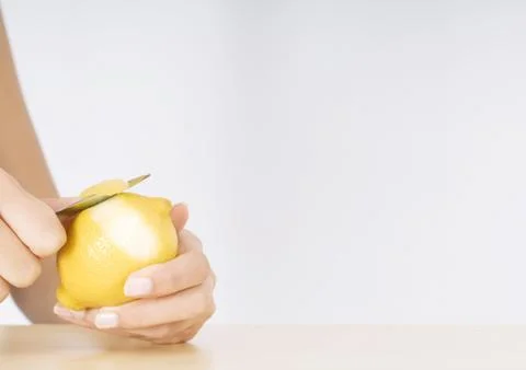 Woman's hands peeling lemon Stock Photos
