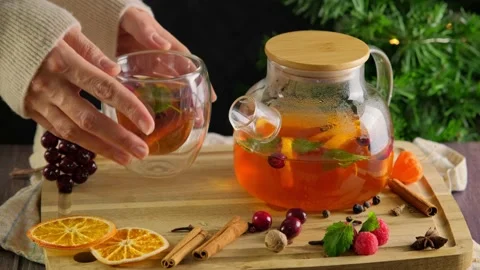 Woman's hands placing a cup with hot fruit tea, flavored with citrus and spice Stock Footage 229325677