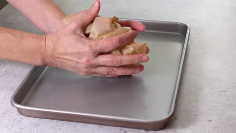 Woman's hands placing parchment paper onto a baking pan Stock Footage 223379664