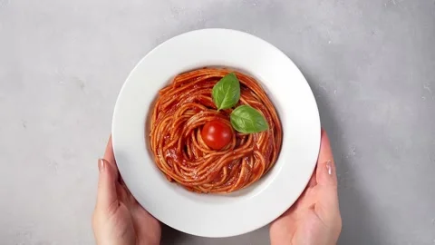 Woman's hands placing plate with spaghetti on a table Stock Footage 143298540
