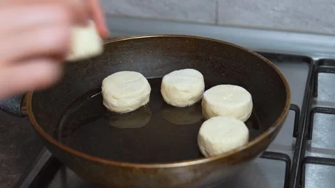 Woman's hands placing raw dough biscuits in hot oil Stock Footage 334152243
