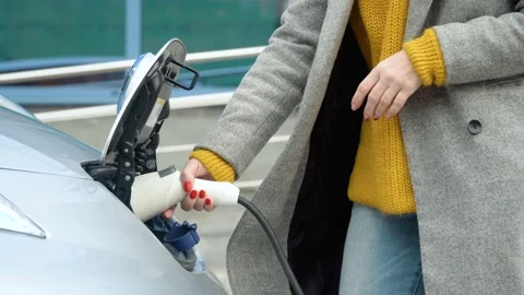 Woman's hands plugging in her electric car to charge. Electrical car recharging Stock Footage 144019682