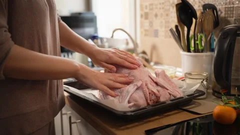 Woman's hands positioning whole raw turkey on parchment-lined baking sheet,.. Stock Footage 344807821