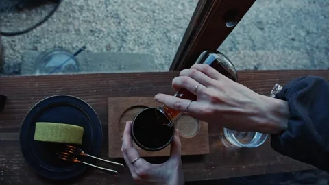 Womans hands pouring tea in cafe with matcha cake Stock Footage 324875765