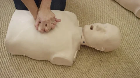 Woman's hands practicing chest compression on dummy in first aid EMT training Stock Footage 168654067