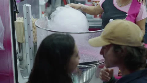 A womans hands prepare cotton candy under the gaze of a couple Video stock 221427295