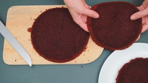 Woman's hands preparing dark chocolate cake layer on wooden cutting board 库存影片 342885485
