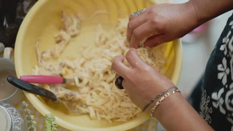 Woman's hands preparing shredded chicken in a kitchen bowl 動画素材 343435820