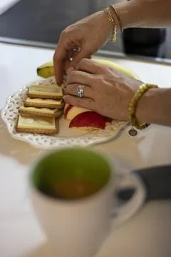 A woman's hands preparing a snack with fruit and biscuits 库存照片