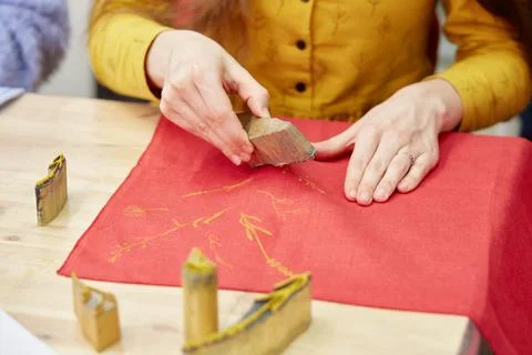 Woman's hands prints a pattern on a fabric with acrylic paint using stamps Stock Photos