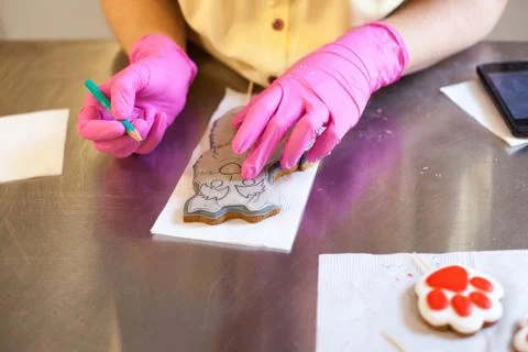 Woman's hands in process of drawing on new year gingerbread cookies on a meta Stock Photos