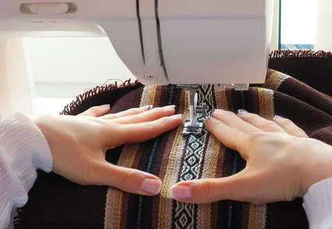 Woman's hands in the process of sewing a colored fabric on the sewing machine Stock Photos
