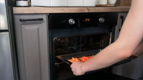 The woman's hands pull the cooked vegetables out of the oven. Stock Footage 196006126