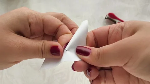 A womans hands pull a metal staple out of a sheet of paper Stock Footage 318390193