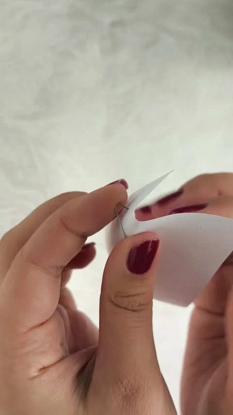A womans hands pull a metal staple out of a sheet of paper Stock Footage 318390595